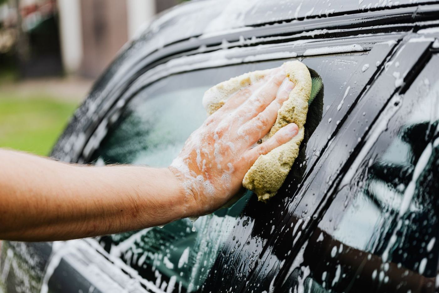 Mobile detailing technician hand-washing a car in a Nolensville driveway